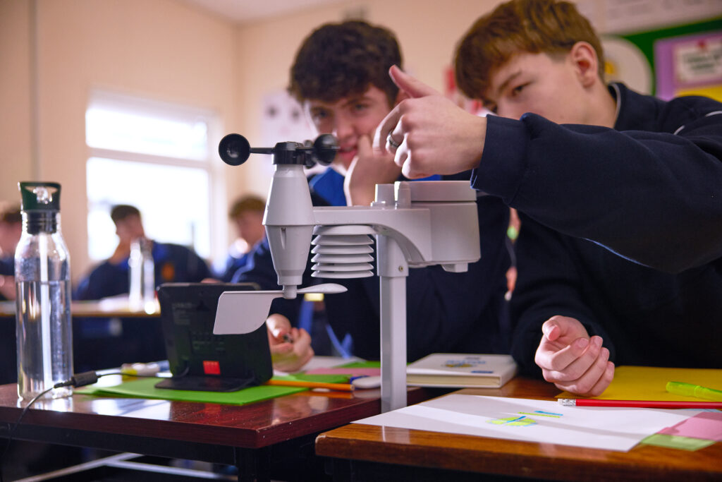 Two students engaging with the Weather Watch programme's weather station, collecting weather data